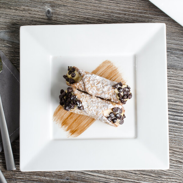 A Bon Chef white bone china square plate with food on a wood table.
