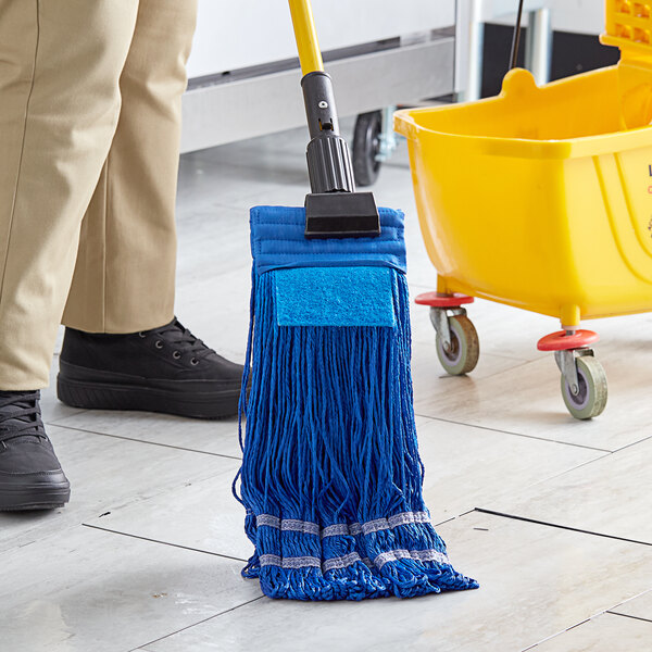 A person using a Lavex blue microfiber looped end wet mop with a black headband to clean a floor.