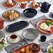 A table with Acopa Keystone stoneware ramekins, plates, and food on it.
