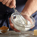 A person using Fox Run mini whisks to mix ingredients in a bowl.