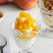 A glass of dessert with I. Rice Georgia Peach topping on a table.